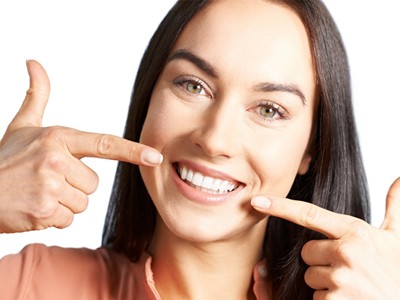 Uma jovem feliz mostrando em sua boca os alinhadores instalados.